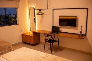 een slaapkamer met een bureau met een laptop en een televisie bij Apart Hotel Roda Viva in Abaeté