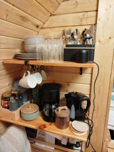 a kitchen with wooden shelves with dishes and utensils at Schlaffass und Tiny House am See, Spa mit Sauna und Hot Tub, angeln, Boot, Natur in Twist