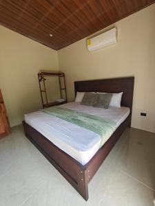 a bedroom with a large bed with a wooden headboard at Casa Lapa in Aguas Zarcas