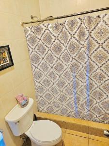 a bathroom with a toilet and a shower curtain at Sunset Views Apartment, West End in West End