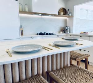 a kitchen with three plates on a counter with two chairs at Barbara's Beach House in Hallidays Point