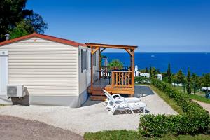 ein Haus mit zwei weißen Stühlen und einer Terrasse in der Unterkunft Orsera Camping Resort by Valamar in Vrsar