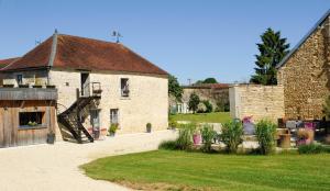 a large stone building with a staircase in a yard at La villa des Chouettes in Maisons-lès-Chaource