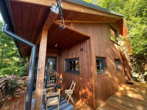 a wooden cabin with a porch and chairs on a deck at Domek nad jeziorem w górach in Międzybrodzie Bialskie
