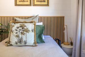 Blissful on Bay by Waiheke Pure في Waiheke Island: سرير عليه وسائد خضراء وبيضاء