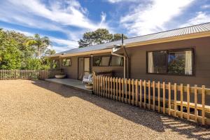 Blissful on Bay by Waiheke Pure في Waiheke Island: منزل أمامه سور خشبي