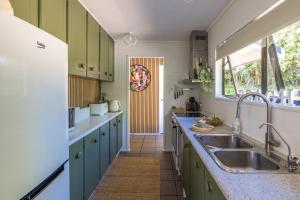 Blissful on Bay by Waiheke Pure في Waiheke Island: مطبخ مع دواليب خضراء ومغسلة +42 صورة