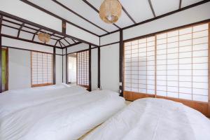 two beds in a room with windows at 温故知新 in Minamiboso