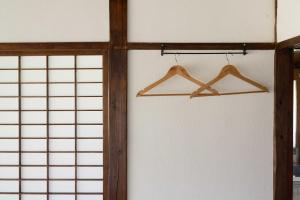 a pair of wooden hangers on a white wall at 温故知新 in Minamiboso