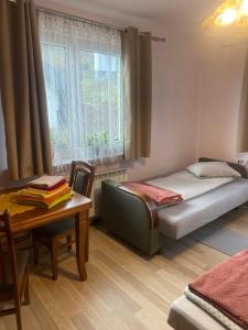 a bedroom with a bed and a table and a window at Pokoje "Pod Lasem" in Balice