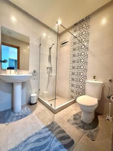 a bathroom with a shower and a toilet and a sink at Luxury and serenity HARHOURA in Temara +2 photos