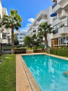 a swimming pool in front of a building with palm trees at Luxury and serenity HARHOURA in Temara