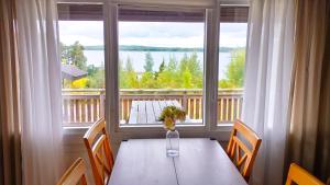 a table with chairs and a large window with a view at Brusta Stugor in Ödkarby