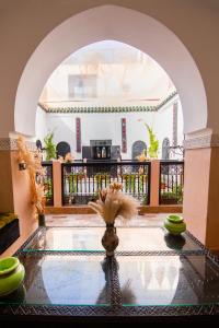 Una habitación con un arco y un jarrón con flores sobre una mesa. en Riad Ta'achchaqa, en Marrakech
