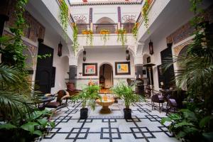 a man sitting in a room with plants in it at Riad Ta'achchaqa in Marrakech
