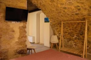 a room with two chairs and a tv on a stone wall at B & B Il bivacco in Assergi