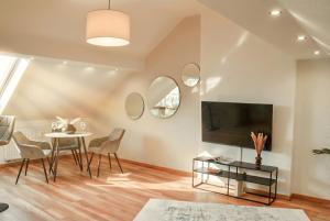 a living room with a table and chairs and a tv at MILPAU Bottrop1 - Zentrales, modernes Design-Apartment - Smart TV, Nespresso, für 4 Personen in Bottrop