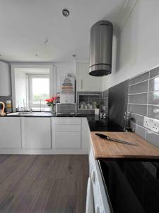 a kitchen with white cabinets and a wooden counter top at Stylish One Bed Apartment in Edinburgh