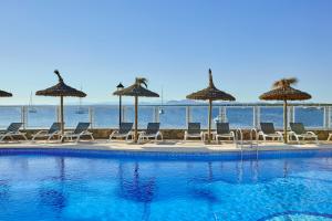 - une piscine avec chaises longues et parasols et l'océan dans l'établissement Universal Casa Marquesa, à Colonia Sant Jordi