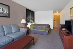 Super 8 by Wyndham Portage La Prairie MB في بورتاج لا بريري: غرفة فندق بها سرير وأريكة