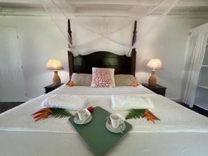 a bed with two cups and a tray with flowers on it at Villa Mandala à 500 m de la plage in Belle-Allée +63 photos
