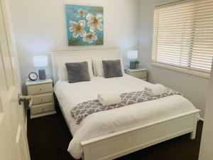 a bedroom with a white bed with two night stands at Bronte Lodge, Wine Country Farm Stay Hunter Valley with Games Room, Close to Town in Greta Main