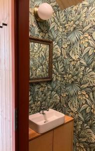 baño con lavabo y papel pintado con motivos florales en Tinyhouse v zahradě,  24 fotos más