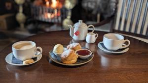 The Kings Arms Hotel في ريث: كوبين من القهوة وأطباق من المعجنات على طاولة