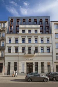 a large white building with cars parked in front of it at Apartamenty MOOD HARMONY Garbary 40 in Poznań