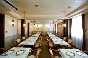 a row of tables in a room with white tablecloths at Shinseto Station Hotel in Seto