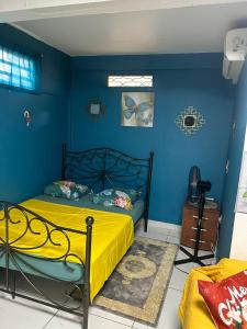 カイエンヌにあるStudio F cosyの青い壁のベッドルーム1室、ベッド1台(黄色いシーツ付)