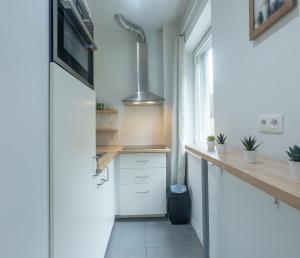 98 Apparthotel - Botanique 3 في لييج: مطبخ مع دواليب بيضاء وميكرويف