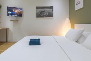 98 Apparthotel - Botanique 3 في لييج: سرير ابيض عليه غرض ازرق