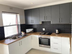 BelharUnit 1 GatherPoint Sleeps 6 Self-Catering Group in Belhar, Cape Town的带白色橱柜和水槽的厨房 更多15张照片