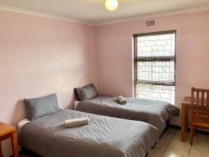 BelharUnit 1 GatherPoint Sleeps 6 Self-Catering Group in Belhar, Cape Town的房间里有两张床，还有一张桌子和一扇窗户