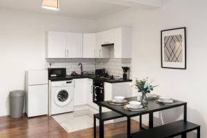 a kitchen with white cabinets and a table and a washer at 1Bed Gem Central Bletchley Perfect for Contractors in Bletchley +17 photos
