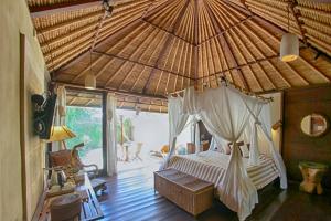 a bedroom with a bed in a straw roof at Visakha Sanur by Puri Signatures in Sanur +179 photos