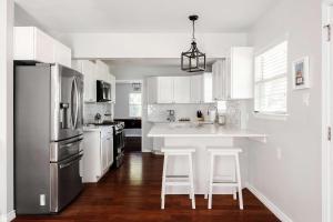 een keuken met witte kasten en een keukeneiland met krukken bij The Oak Haven - 3BR with Pool Billiards & Arcade in Austin