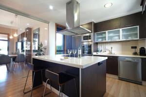 una cucina con una grande isola con sgabelli da bar di GALIHOST - Villa Gandara a Ribadumia