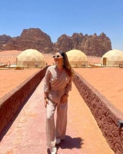 a woman standing next to a wall in the desert at Camp in Wadi Rum in Maḩaţţat Dīsah