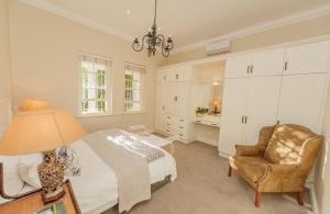 una camera con letto, sedia e lampada di Charming Historic Home in Central Stellenbosch a Stellenbosch