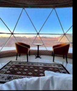a room with two chairs and a table and a large window at Camp in Wadi Rum in Maḩaţţat Dīsah +8 photos