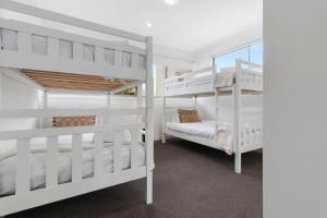 Laguna by Khove في غولد كوست: سريرين بيض بطابقين في غرفة مع نافذة