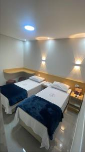 two beds in a room with lights on the wall at Hotel Ellos - Estacionamento e Café da Manhã Incluso in Itaquaquecetuba