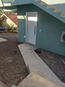 Loft Serra Gaúcha-Bem estar no coração de Nova Petrópolis في نوفا بتروبوليس: باب أبيض على جدار أخضر بجوار منزل