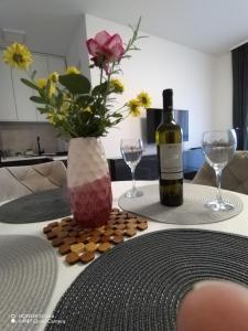 een tafel met een fles wijn en een vaas met bloemen bij Splendid J&R apartman in Bijeljina