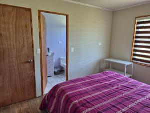 a bedroom with a purple bed and a bathroom at Cabaña Tranquilidad en Familia in Chillán