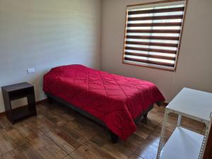 a bedroom with a red bed and a window at Cabaña Tranquilidad en Familia in Chillán
