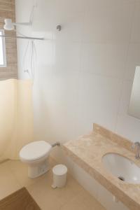 a white bathroom with a toilet and a sink at Palace Massaguaçu in Caraguatatuba