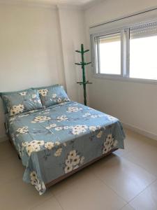 a bedroom with a bed with a blue comforter and a window at Apê da Paula in Torres +19 photos